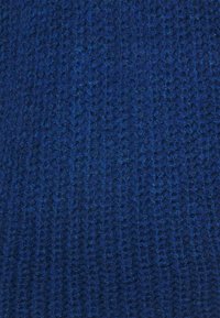 Włóczkowy materiał w głębokim niebieskim kolorze z teksturowanym, falistym wzorem. Materiał wydaje się miękki i lekko puszysty, co sugeruje ciepło i komfort.