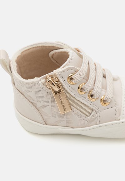 Helle beige High-Top-Sneaker mit strukturierter Oberfläche, goldenen Beschlägen, dekorativem Reißverschluss und cremfarbenen Schnürsenkeln. Weiches Innenfutter ist sichtbar.