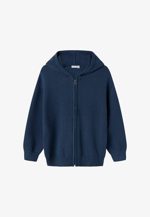 Tamna plava zip-up dukserica s mekanom teksturom, rebrastim manžetama i kapuljačom s vezicom. Ima središnji patentni zatvarač i opušteni kroj.