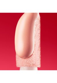 Aplikator do makijażu z zaokrągloną, brzoskwiniową gąbeczką i miękkimi, puszystymi różowymi włosiem, na tle jasnoczerwonym.