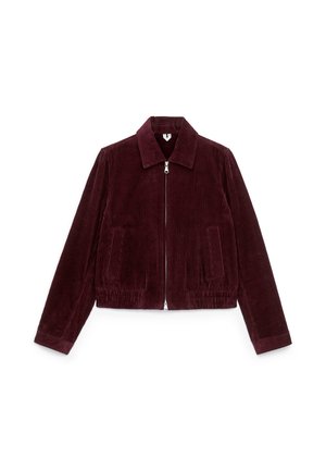 Burgunderfarbene Cordjacke mit geradem Schnitt, Frontreißverschluss, zwei seitlichen Taschen und klassischem Kragen. Ribbeltextur über die gesamte Oberfläche.