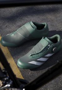 Green cycling shoes with a sleek design, featuring a smooth texture, a secure closure system, and white accents on the sides.