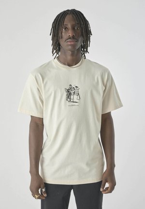 Cream-colored t-shirt in cotton, featuring a central black graphic print. Short sleeves and a relaxed fit with a round neck.