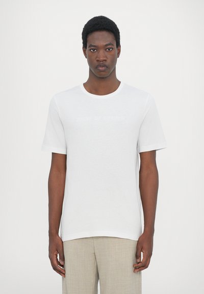 White short-sleeve t-shirt made of soft cotton, featuring a round neckline and subtle logo text in light gray. Clean, minimal design.