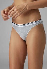 Svetlosivé bavlnené tangá s mäkkým elastickým pásom, na ktorom je biele slovo „next“ kontrastujúce s čiernym pruhom.