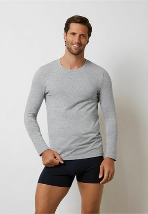 Lichtgrijze longsleeve t-shirt met een fitted ontwerp en een ronde hals, gemaakt van een zachte katoenmix, gecombineerd met donkerblauwe shorts.