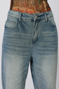 Jeans de mezclilla azul claro con un lavado desgastado, que cuentan con cinco bolsillos, un cierre de botón metálico y un diseño de pierna recta.