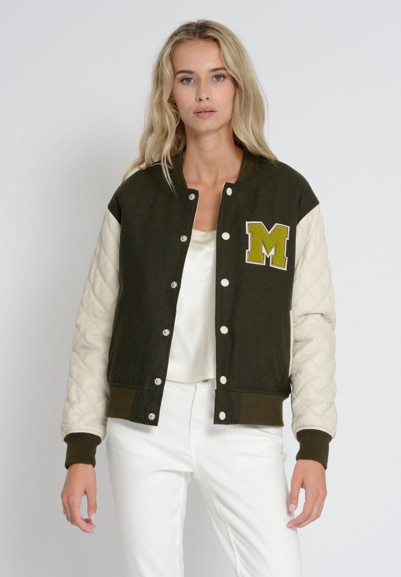 Grøn og flødefarvet varsity-jakke med quiltet tekstur, trykknapper og et broderet gult "M" logo på brystet.