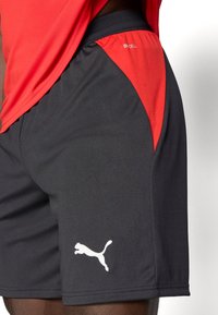 Μαύρο αθλητικό σορτς με κόκκινες λεπτομέρειες, από υφή υφάσματος και λευκό λογότυπο Puma στο αριστερό πόδι. Διαπνέον υλικό Dri-Cell.