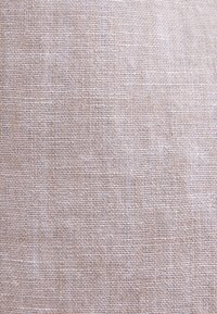 Tissu beige tissé avec un motif en grille texturé créé par des fils horizontaux et verticaux entrelacés.