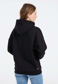 Felpa nera con cappuccio grande, vestibilità comoda e polsini a coste. Il materiale sembra morbido con un design minimalista. Piccolo logo sull'orlo.