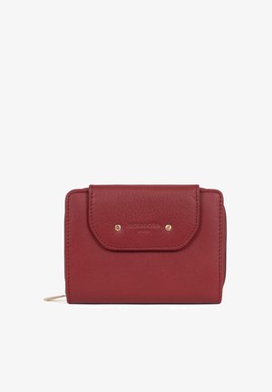Kompaktowy czerwony skórzany portfel z przednią klapką zabezpieczoną dwoma mosiężnymi ćwiekami oraz zamkiem błyskawicznym z boku.