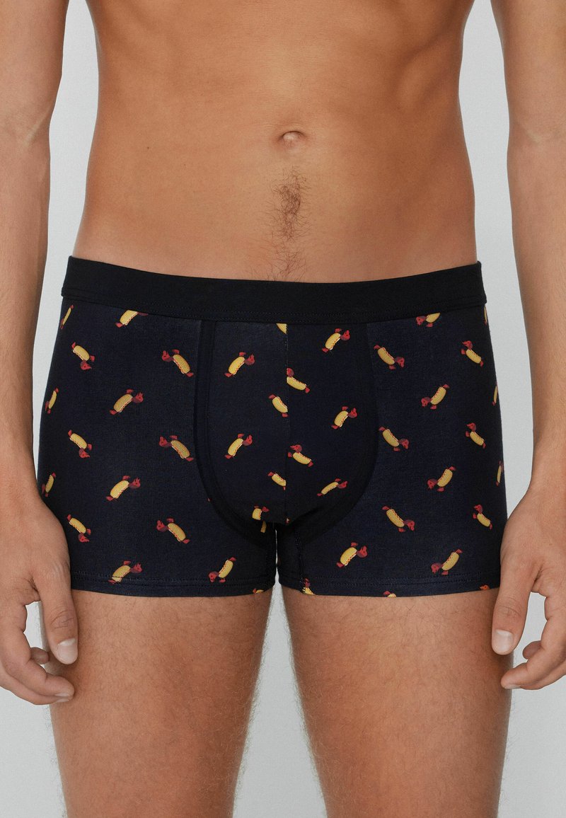 Pánské boxerky v tmavě námořnické barvě s opakujícím se vzorem žlutých párků s červenými akcenty. Elastický pas, přiléhavý střih.