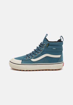Tenis de cano alto feitos de camurça azul com pormenores em pele branca. Apresenta uma sola em borracha, forro interior preto e detalhes de costura proeminentes.