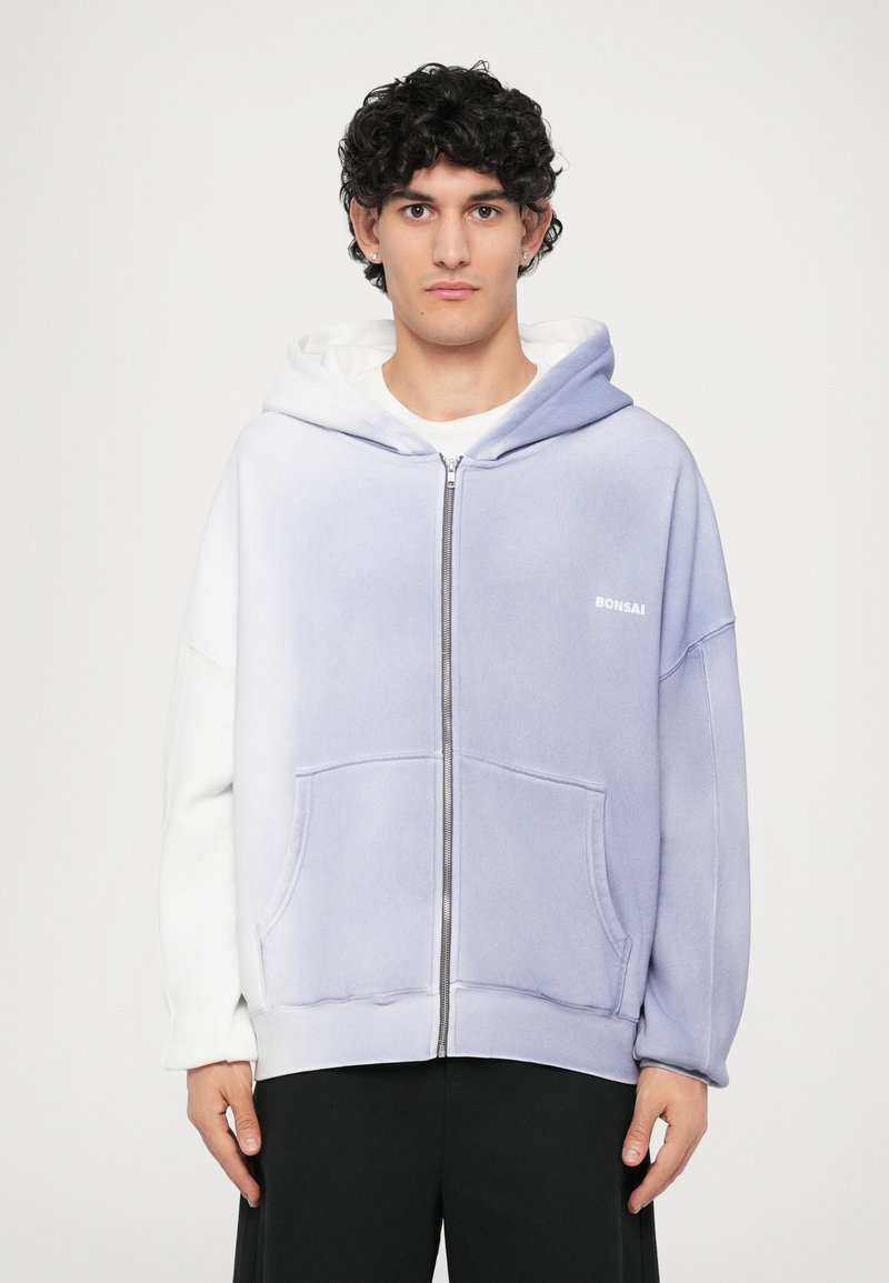 Hætte sweatshirt med lynlås i lys lilla og hvid, med en blød tekstur, frontlommer og "Bonsai" logo på brystet.