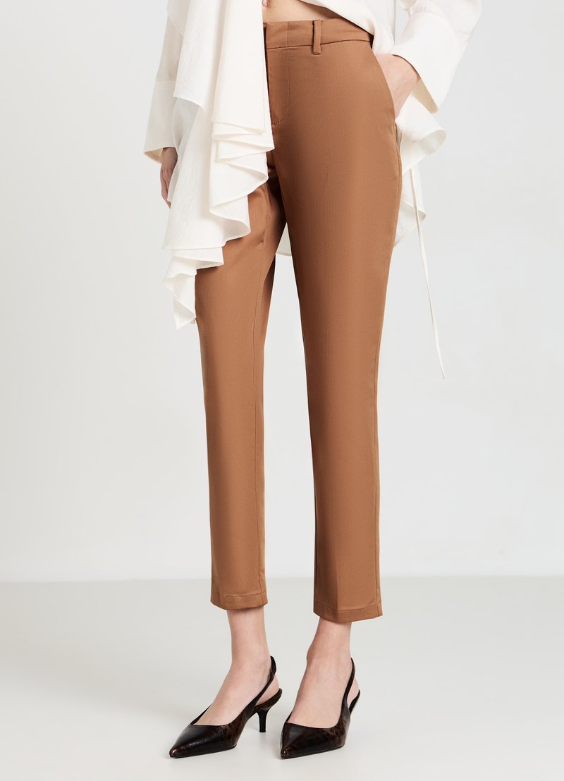 Braune maßgeschneiderte Hose mit schmaler Passform, glatter Textur und mittelhohem Bund, kombiniert mit schwarzen Lackleder-Slingback-Absätzen.