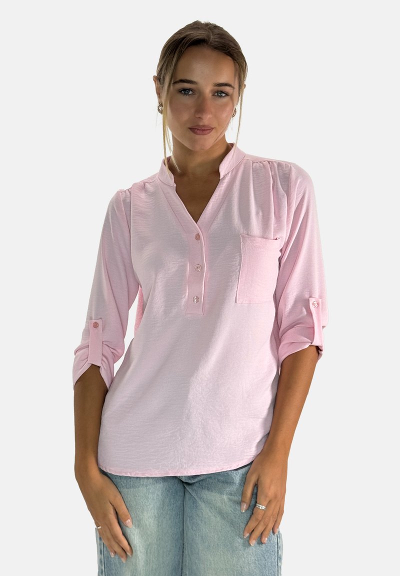 Jasnoróżowa bluzka z długim rękawem, z dekoltem henley, z guziczkami i kieszenią na piersi. Posiada podwinięte rękawy oraz fakturowany materiał.