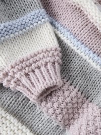 Mehrfarbiger gestrickter Pullover mit breiten Streifen in Grau, Weiß, Hellblau und Hellrosa. Mit gerippten Bündchen und weichem, strukturiertem Stoff.