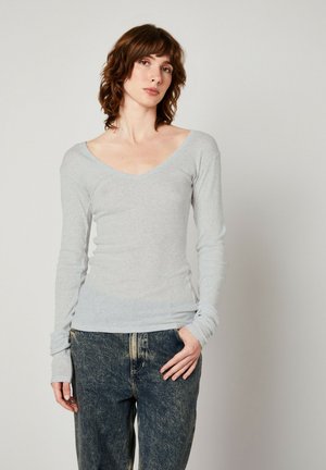 Grau langärmliges V-Ausschnitt-Oberteil aus weichem Stoff, taillierte Form, mit subtiler Textur und enganliegenden Bündchen, kombiniert mit blauen lässigen Jeans.