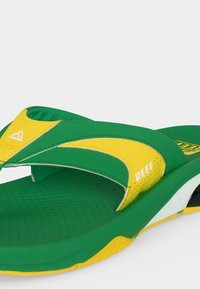 Πράσινο και κίτρινο σανδάλι Reefs με υφή στην εσωτερική σόλα και μαλακή σόλα, λοξή όψη που δείχνει το λουράκι και το λογότυπο της μάρκας.