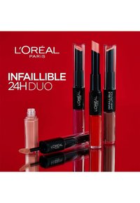 Produits de lèvres Duo Infallible 24H de L'Oréal Paris dans des tubes noirs élégants avec des bouchons transparents, présentant des teintes de nude, rose, rouge et marron.