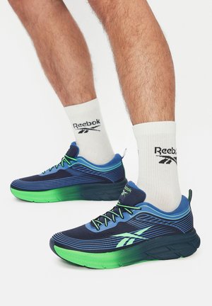 Granatowo-zielone buty do biegania z siateczkową cholewką, teksturowanymi paskami, amortyzowaną podeszwą i czarnymi sznurówkami. Noszone z białymi skarpetami z logo.