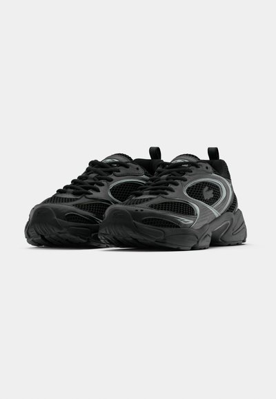Chaussures de sport noires dotées d'une tige en mesh, d'une semelle en caoutchouc, d'un design à lacets prononcé, d'accents réfléchissants et d'une forme d'orteil arrondie.