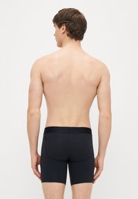 Fekete rövidnadrág rugalmas anyagból, sima textúrával, elasztikus derékpánttal és testhezálló kialakítással a kényelemért.