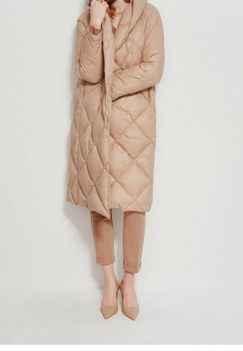 Beige quilted long coat with a hood, featuring snap closures. Paired with light beige cropped trousers and pointed toe heels. Smooth texture.