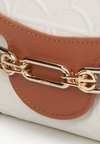 Hnědá kožená kabelka s pozlaceným řetězovým kováním a texturovaným bílým tělem se jemnými vzory.