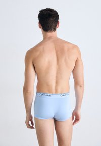 Helle blaue Baumwoll-Boxershorts mit einem schwarzen, gebrandeten Bund, glatte Textur und enganliegendem Design, von hinten gezeigt.