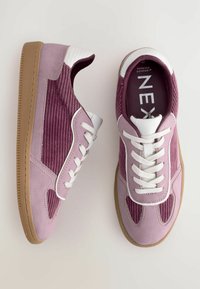 Lila mockasinsneakers med kordflosseraccent, vita snörningar och tan gummisula. Har en quiltad design och vadderad krage.