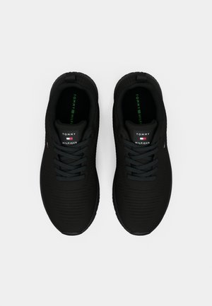 Para czarnych sneakersów Tommy Hilfiger ze sznurówkami, widziana z góry na jednolitym jasnym tle.