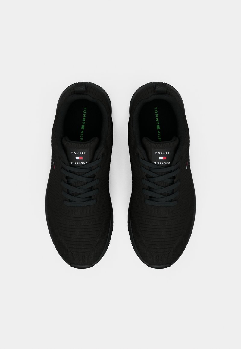 Paire de baskets noires Tommy Hilfiger avec lacets, vues de dessus sur un fond clair uni.