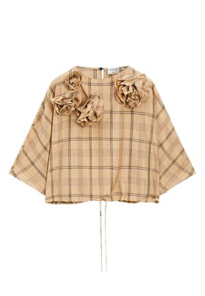 Top à carreaux beige avec des accents floraux bouffants, coupe ample, encolure arrondie et ourlet à cordon. Tissu texturé qui favorise un look décontracté.