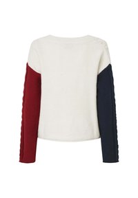 Pull en maille blanche à manches longues, une manche rouge foncé et l’autre bleu marine, avec un subtil détail en torsades.