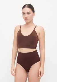 Top corto marrone con spalline sottili e pantaloni a vita alta coordinati. Tessuto liscio, design minimalista e tessuto elastico.