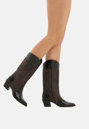 Braune Wildlederstiefel bis zum Knie mit glänzendem schwarzen Krokodil-Textur an der Oberseite und spitzer Zehenform, niedriger Blockabsatz und Reißverschlussdetails.