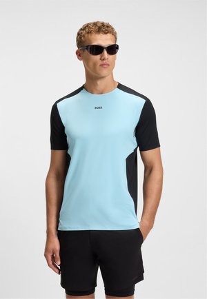 Lyseblå træningsskjorte med sorte accenter, korte ærmer, struktureret stof og "BOSS" logo på brystet, parret med sorte shorts.