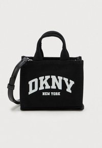 Μαύρη τσάντα tote της DKNY με κοντούς χειρολαβές, αποσπώμενο μαύρο λουρί και το λογότυπο "DKNY New York" εκτυπωμένο σε λευκό μπροστά.