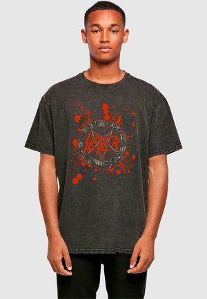 Black oversized t-shirt made of cotton, featuring a red graphic with splatter patterns and "Slayer" text in a circular design.