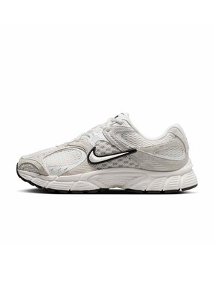 Λευκό και ανοιχτό γκρι παπούτσι τρεξίματος Nike με μαύρο λογότυπο Swoosh, επάνω μέρος από δίχτυ και σουέτ, και υφασμένη σόλα σε πλευρικό προφίλ.