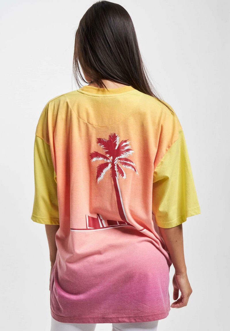 T-skjorte med korte ermer, oversized design, som har en gradient fra gul til rosa, med et palmetre grafikk på baksiden og en glatt bomullstekstur.