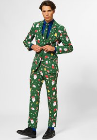 Completo verde con motivi natalizi, che presenta Babbo Natale, bastoncini di zucchero e fiocchi di neve. Abbinato a una camicia blu e scarpe nere.