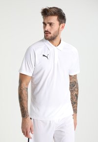 Polo bianco realizzato in tessuto leggero. Presenta un colletto a punta e un logo Puma nero sul lato sinistro del petto. Maniche corte, vestibilità atletica.