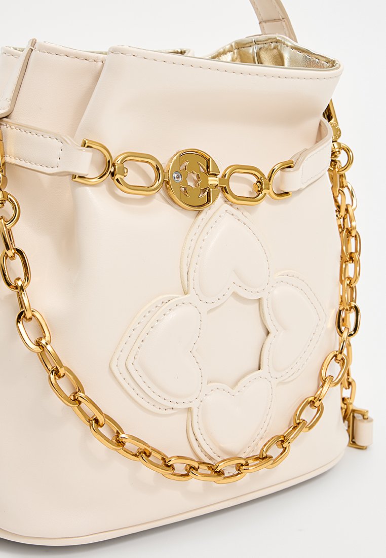 Cremefarbenes Lederhandtasche mit goldener Kettenriemen und Verschluss, mit gestickten Herzformen, die ein Blumenmuster auf der Vorderseite bilden.