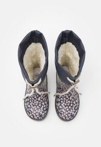 Botas de goma de patrón floral en color marino con un suave forro de lana, cordones gris claro y puntera redondeada. Parte superior elástica para un ajuste ajustable.