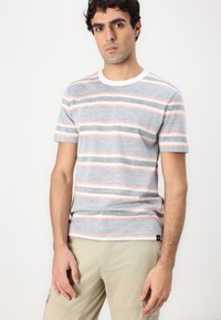 Grå kortermet t-skjorte med horisontale striper i rosa, hvitt og grått. Har rund hals og et merke på siden. Myk tekstur.