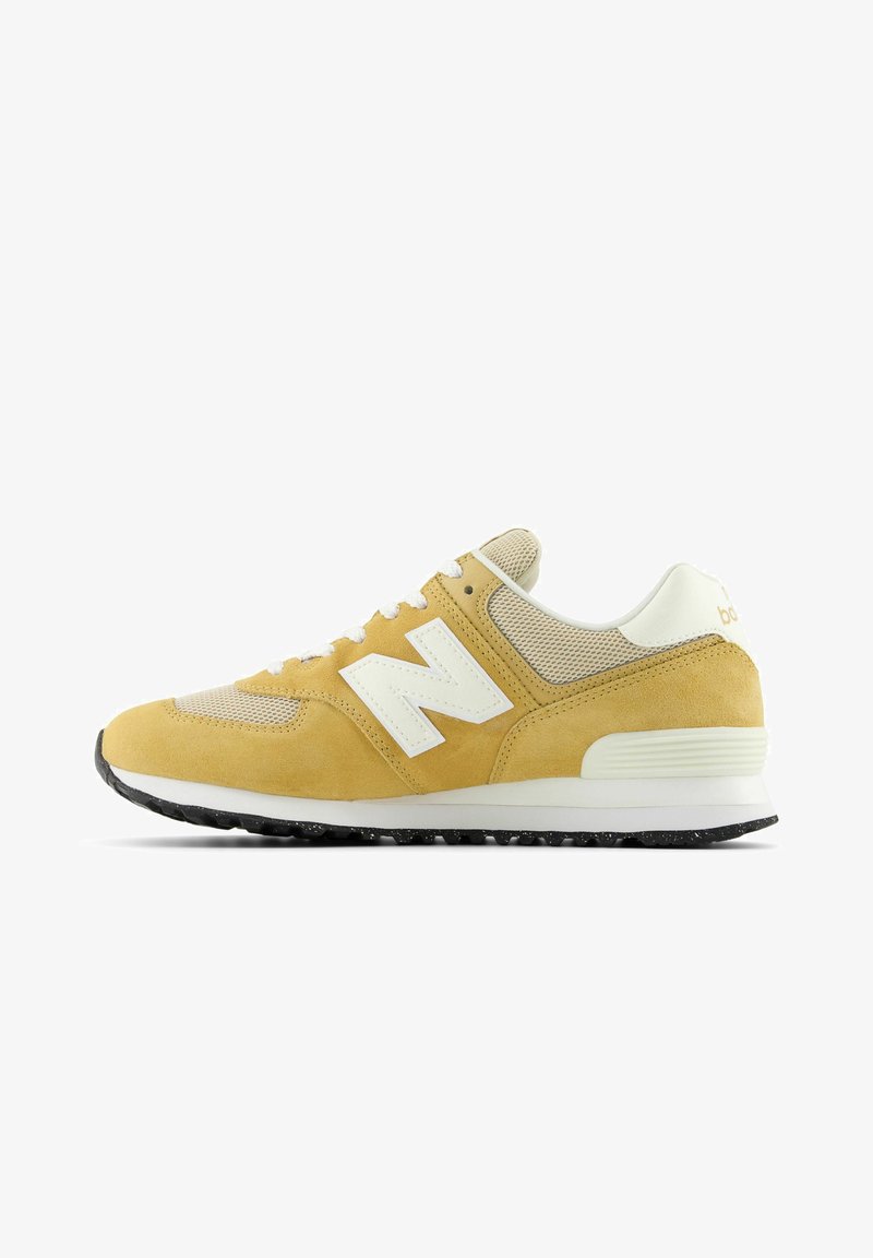 Zapatillas amarillas de ante con paneles de malla, acentos blancos y una suela negra texturizada. Presentan cordones y un destacado logo 'N' en el lateral.