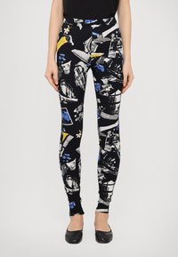 Svarta leggings med en collage av bilder i blått, vitt och gult, med en åtsittande design och slät textur.